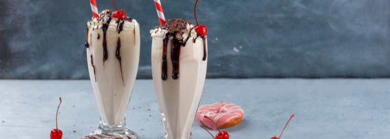 Two chocolate milkshakes with cherries